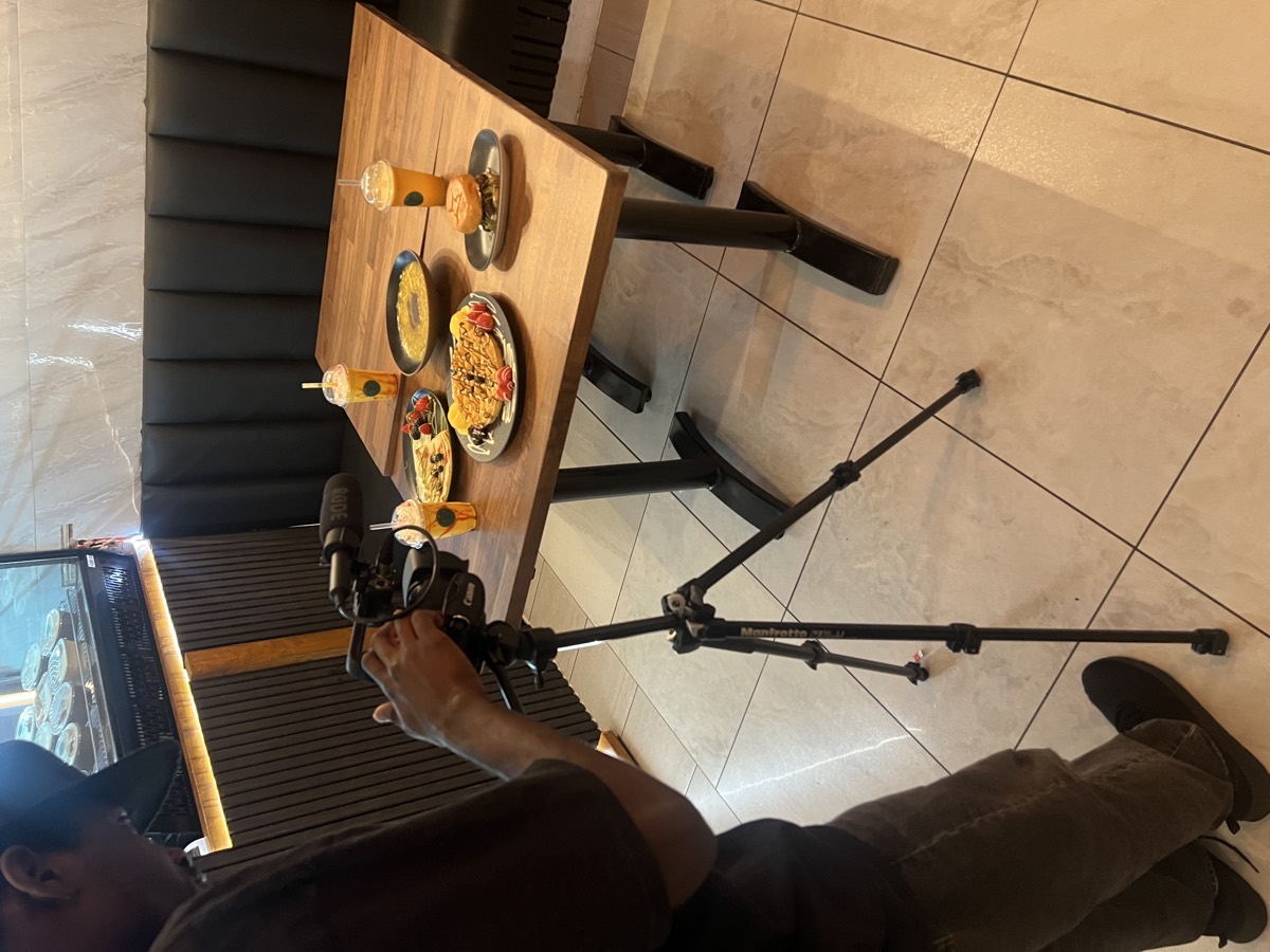 A camera on a tripod filming a table of food at a Birmingham restaurant