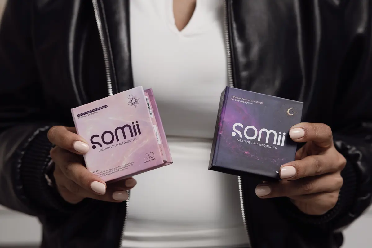 Two hands holding Somii's morning and evening strip boxes in front of a leather jacket